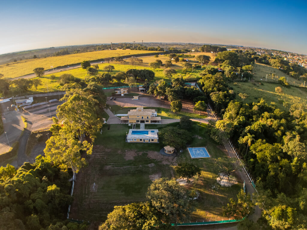 Vista aérea da propriedade ao entardecer, cercada por árvores