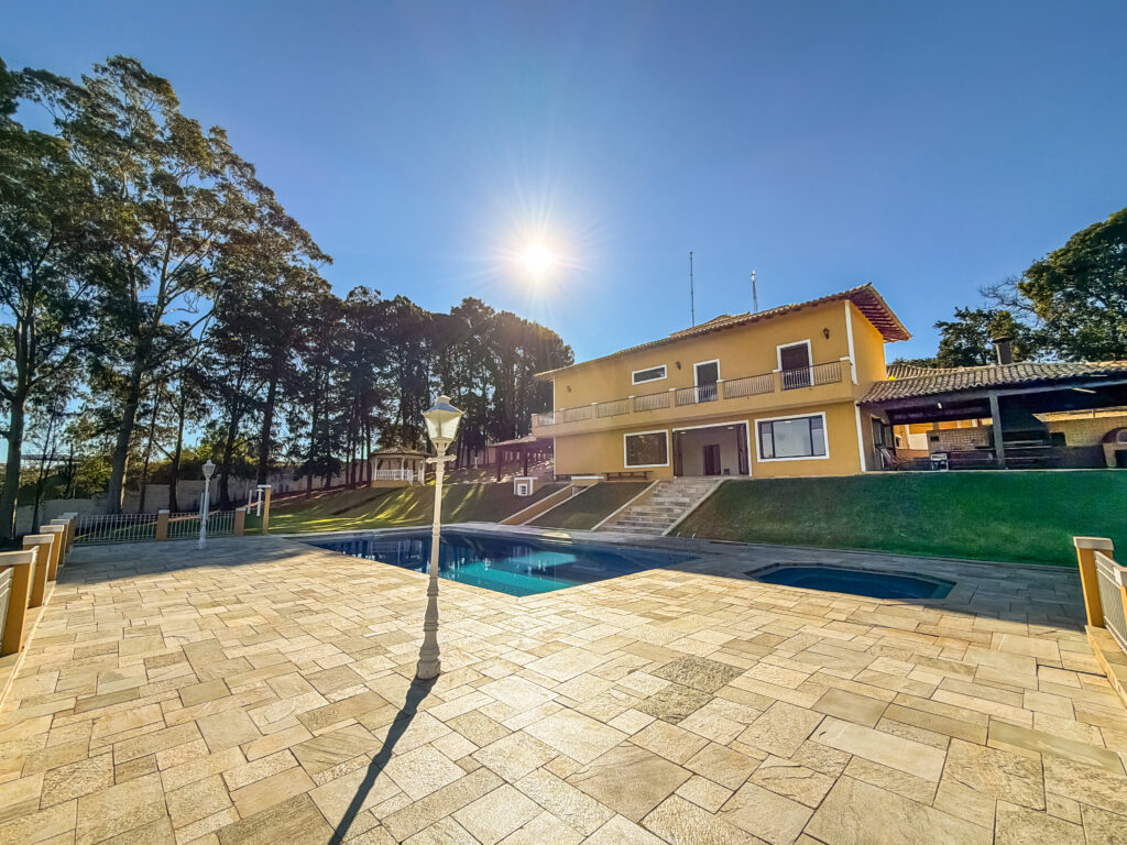 Área da piscina ao entardecer, com a casa ao fundo